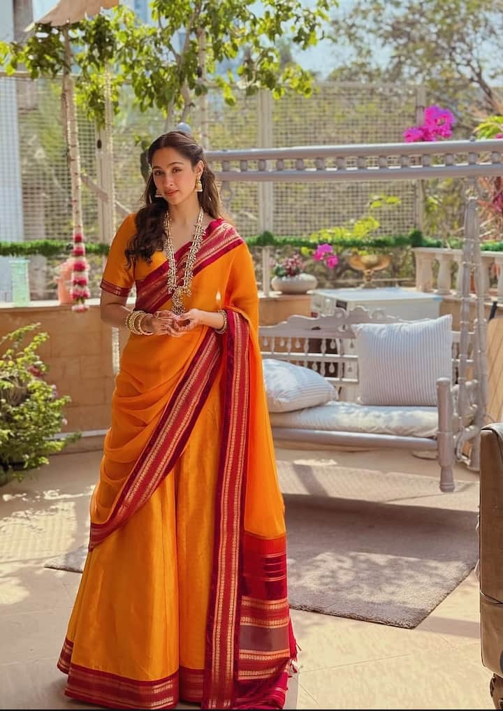 ऑरेंज साड़ी और लाल बॉर्डर वाला पश्मीना का यह लुक पूरी तरह फेस्टिव है. साड़ी के साथ ट्रेडिशनल जूलरी उनके लुक को और निखार रही है. अगर आपको पूजा या परिवार के साथ होने वाली छोटी-सी गैदरिंग के लिए कुछ ट्रेडिशनल पहनना है, तो इस तरह की ब्राइट साड़ी एक अच्छा आइडिया हो सकती है.