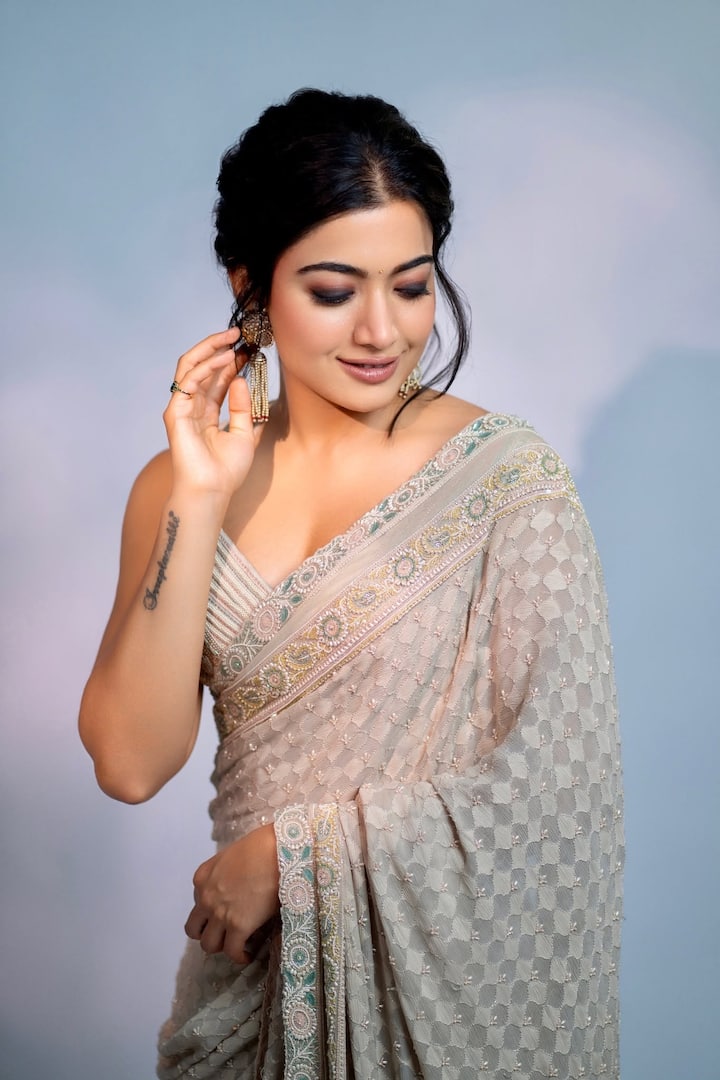इस ग्रेइश व्हाइट शेड की साडी में रश्मिका मंदाना कहर ढ़ा रही हैं. उन्होंने इस लुक को बैलेंस करने के लिए मिनिमल एक्सेसरीज पहनी है. वहीं उन्होंने बालों का स्टाइलिश बन बनाया हुआ है और कुछ लटें आगे निकली हुईं हैं. उनका आई मेकअप भी काफी अट्रैक्टिव है. आप नवरात्रि में कुछ ऐसा भी पहन सकती हैं.